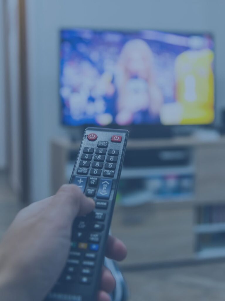 Hand holding remove control pointing at TV.