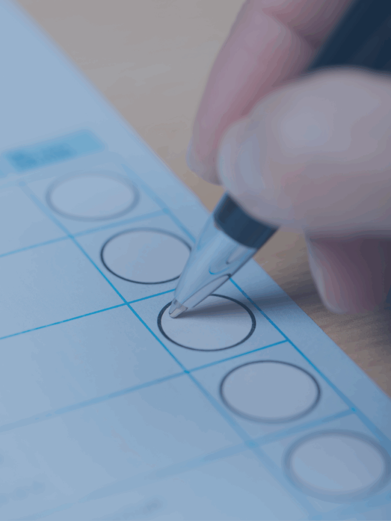 Human hand placing a piece of paper in a box like a ballot box.